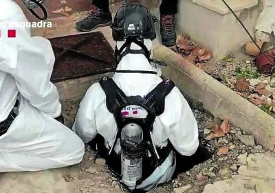 Mossos bajando a la fosa séptica para rescatar el cadáver